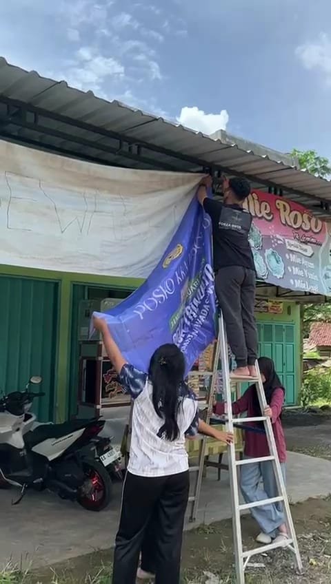 Memasang banner kelompok KKN Unsoed desa Trimulyo