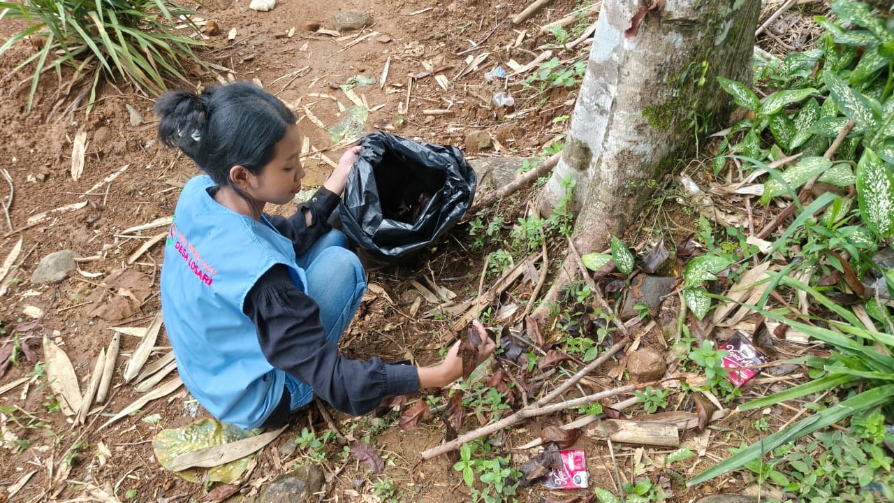 Mengumpulkan daun kering untuk persiapan bahan pembuatan pupuk kompos