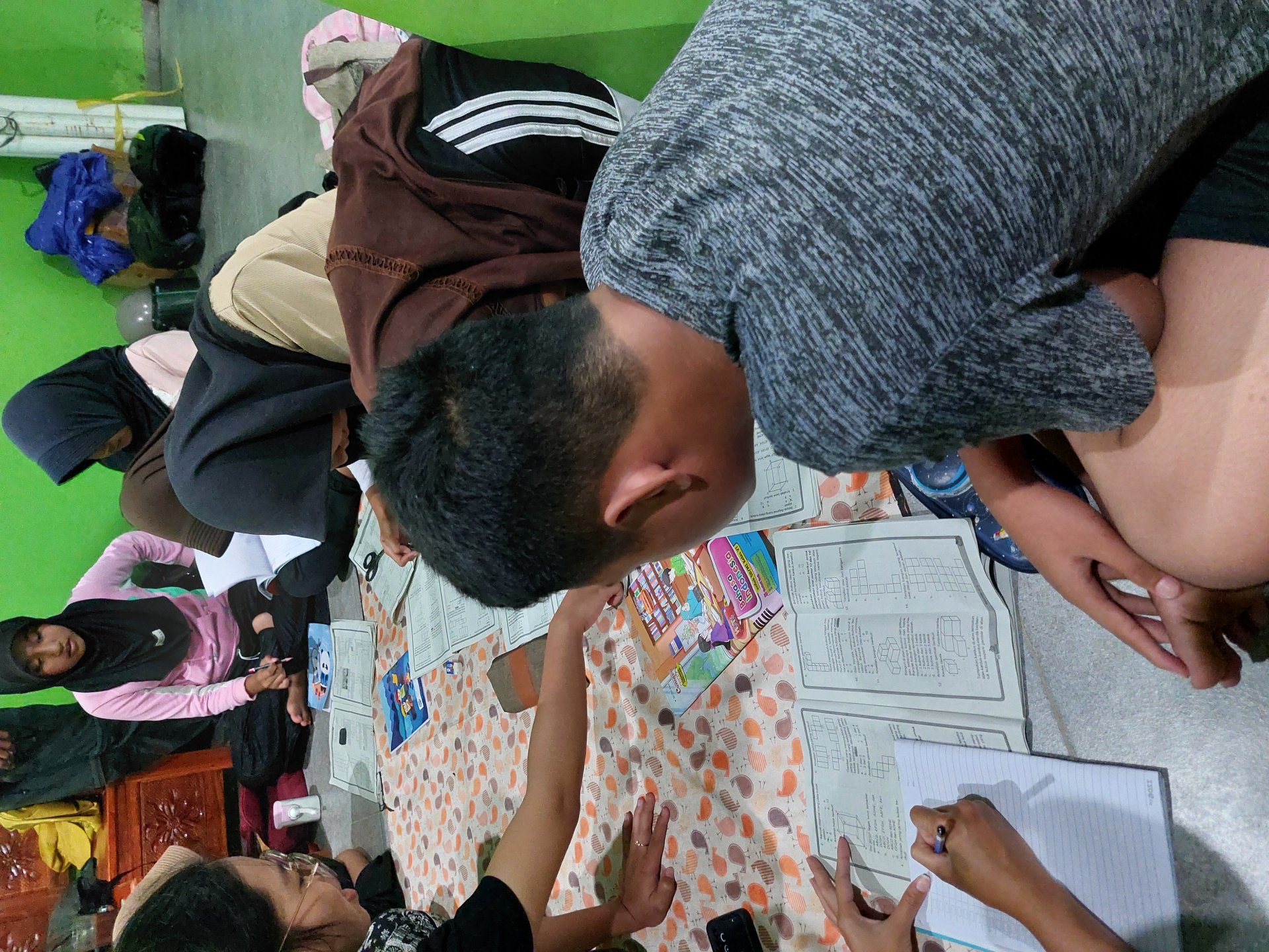 Membantu mengerjakan PR anak-anak di sekitar posko